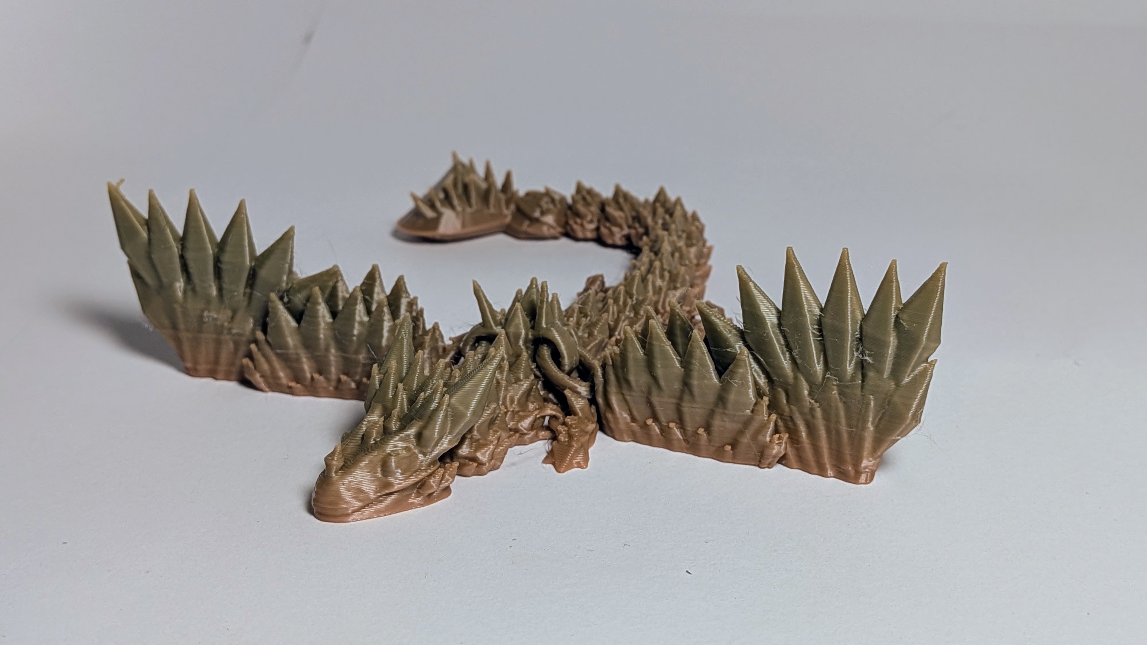 3D printed articulated chaos dragon with thorny spikes in olive and bronze